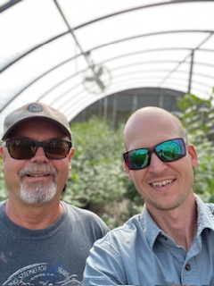 Two men smiling inside a DeGrandchamp Farms greenhouse tunnel